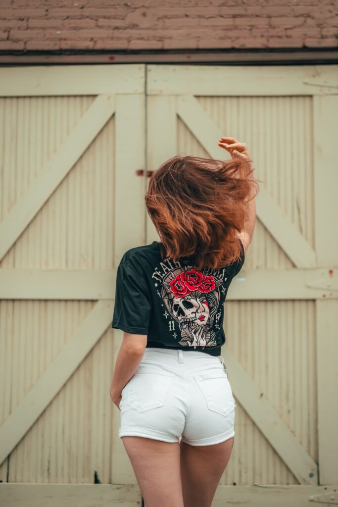 A woman with her back turned wearing white shorts and a tee with a gothic design on the back. Show off your personality while you complete the Halloween bucket list.